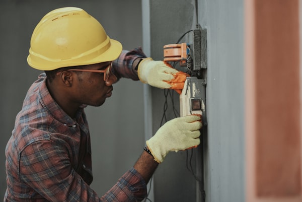 Skilled technician measuring electrical panel circuits safely with PPE