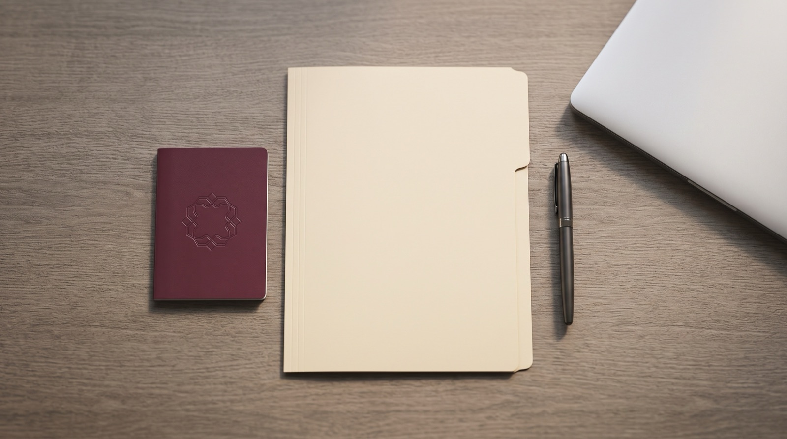 A passport and document folder arranged neatly on a desk beside a laptop